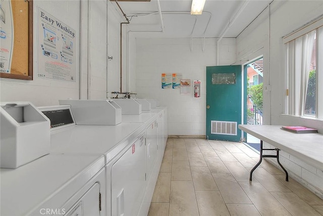 clothes washing area featuring light tile patterned floors and washer and clothes dryer