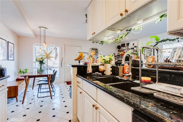 kitchen featuring dishwasher, dark stone countertops, pendant lighting, sink, and white cabinetry