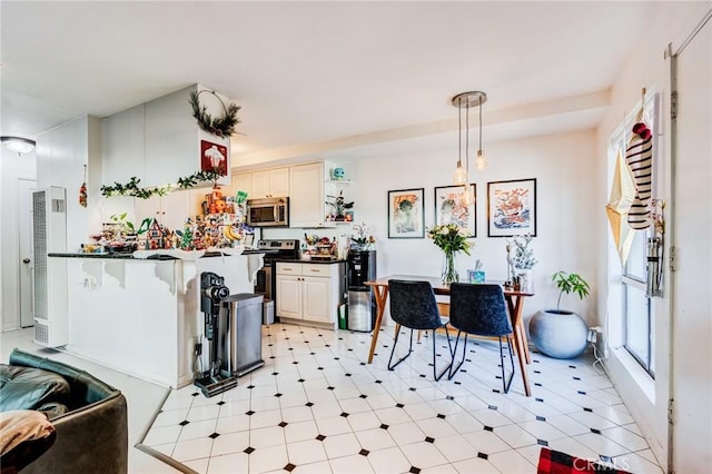 kitchen with kitchen peninsula, appliances with stainless steel finishes, white cabinetry, and pendant lighting