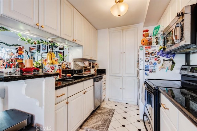 kitchen featuring stainless steel appliances, white cabinetry, dark stone counters, and sink