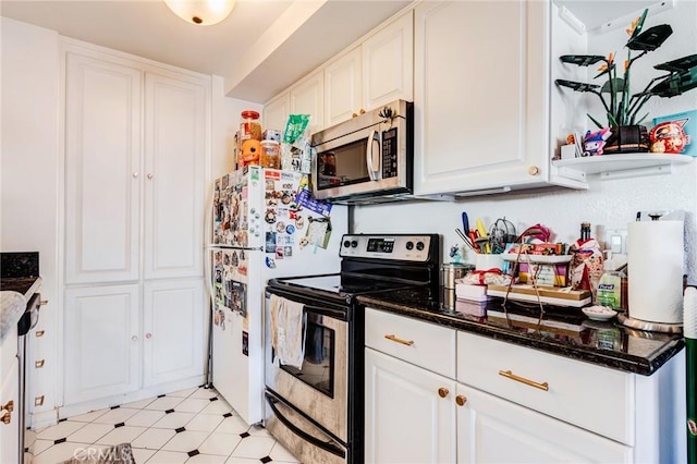 kitchen with white cabinetry, stainless steel appliances, and dark stone countertops