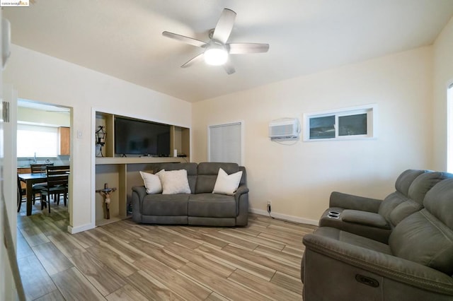 living room with ceiling fan, a wall mounted air conditioner, and light wood-type flooring