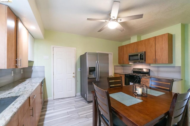 kitchen with ceiling fan, appliances with stainless steel finishes, and light stone counters