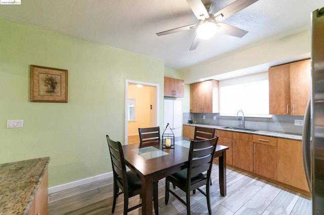 dining room with light wood-type flooring, ceiling fan, and sink