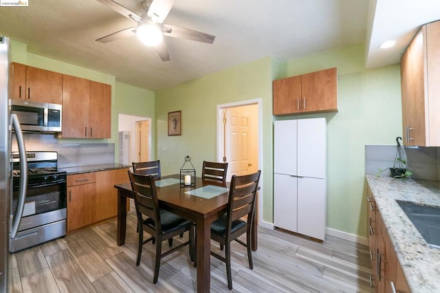 kitchen with ceiling fan, tasteful backsplash, sink, stainless steel appliances, and light stone counters