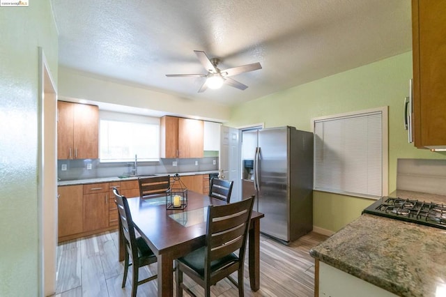 kitchen featuring stainless steel fridge, sink, a textured ceiling, and light hardwood / wood-style flooring