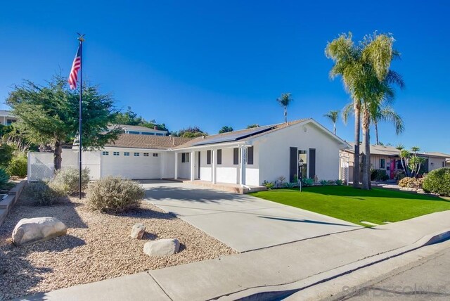 ranch-style house with a front lawn, solar panels, and a garage