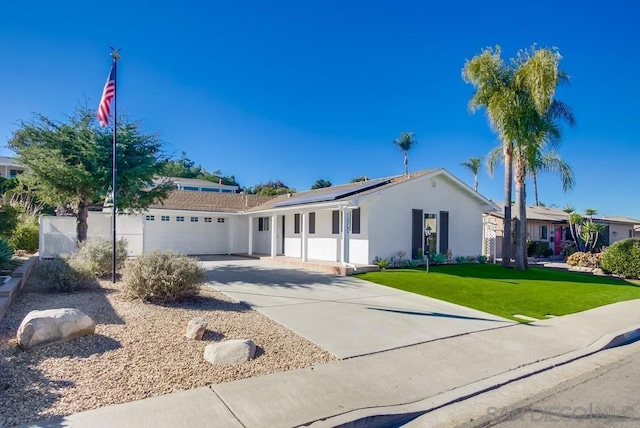 ranch-style house featuring a garage, a front lawn, and solar panels