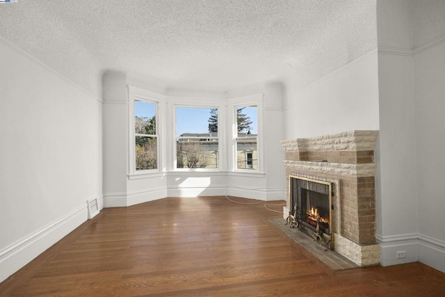 unfurnished living room featuring a textured ceiling, a brick fireplace, and hardwood / wood-style flooring