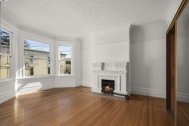 unfurnished living room featuring a fireplace, a textured ceiling, and hardwood / wood-style flooring