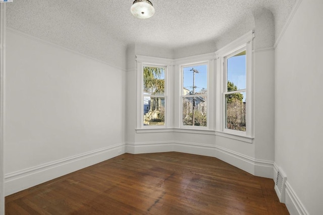 spare room featuring a textured ceiling and dark hardwood / wood-style floors