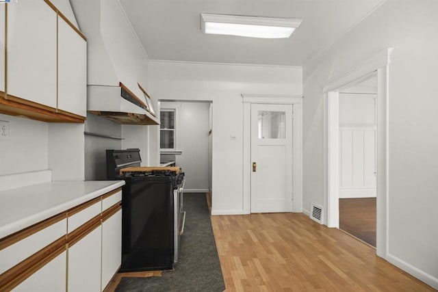 kitchen featuring white cabinets, light wood-type flooring, and gas stove