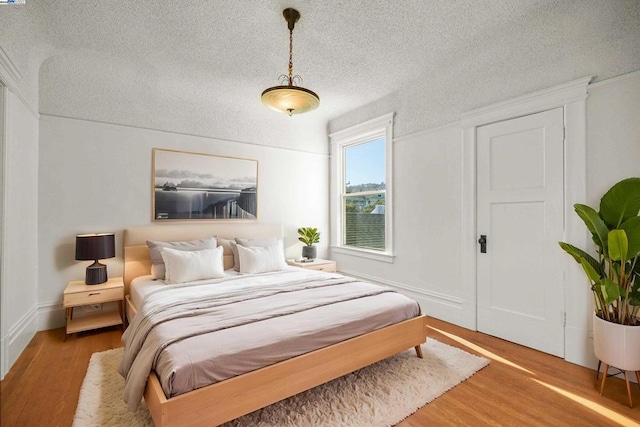 bedroom with a textured ceiling and wood-type flooring