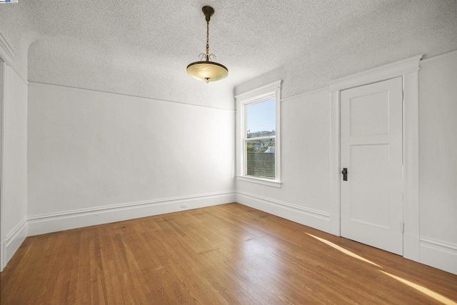 unfurnished room with a textured ceiling and wood-type flooring