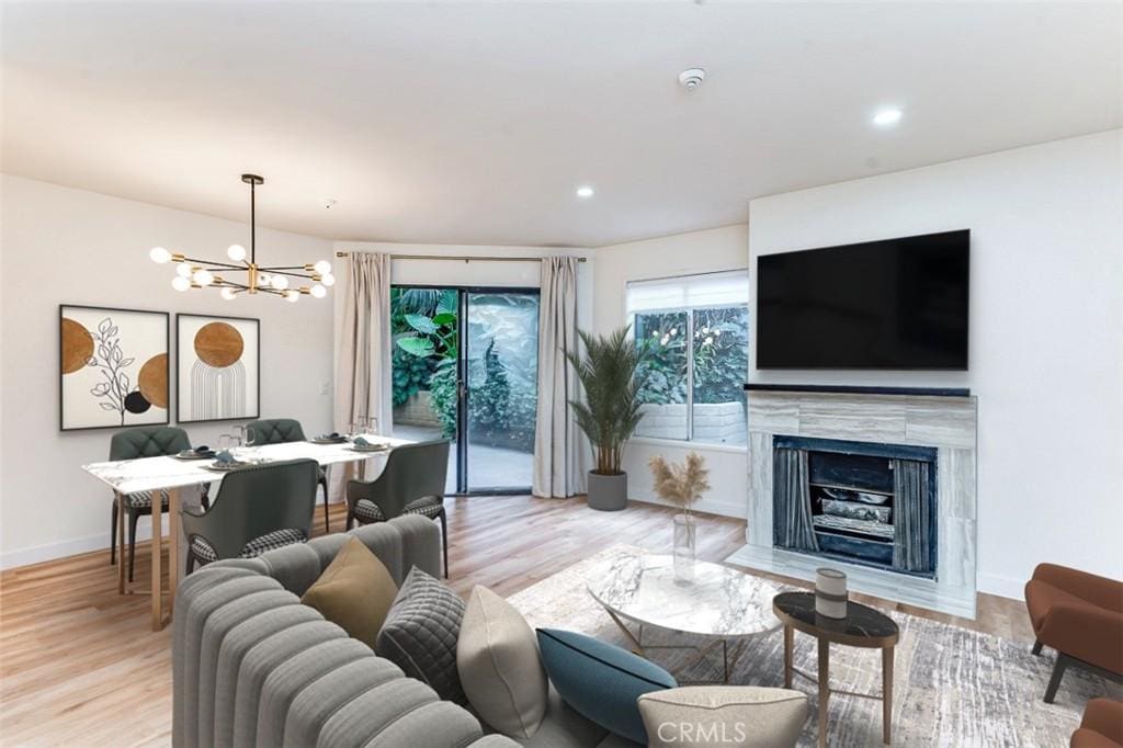 living room with light wood-type flooring, a tile fireplace, and a chandelier