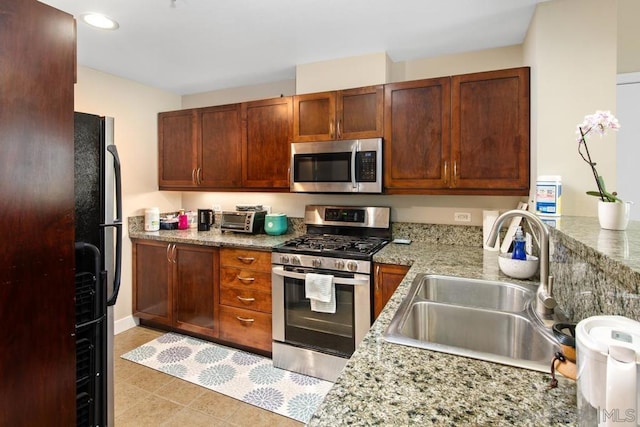 kitchen with light stone countertops, sink, light tile patterned floors, and stainless steel appliances