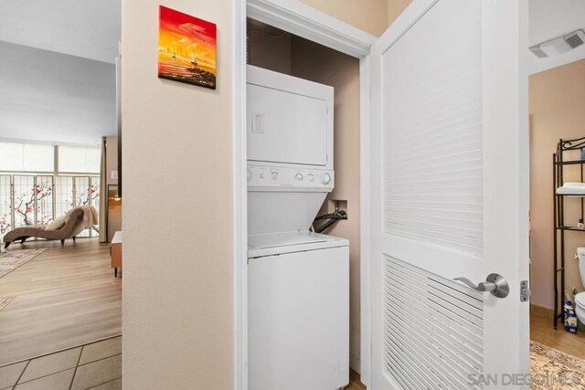 washroom with stacked washer / dryer and light tile patterned floors