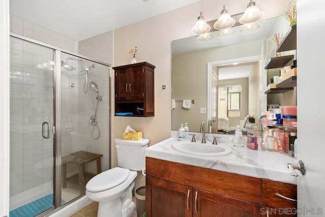 bathroom with toilet, vanity, and a shower with door