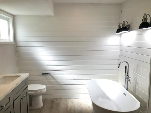 bathroom featuring toilet, a tub to relax in, hardwood / wood-style flooring, and vanity