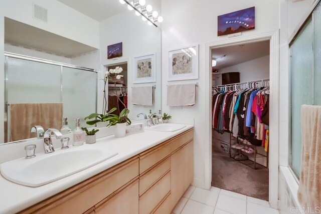 bathroom with walk in shower, vanity, and tile patterned flooring