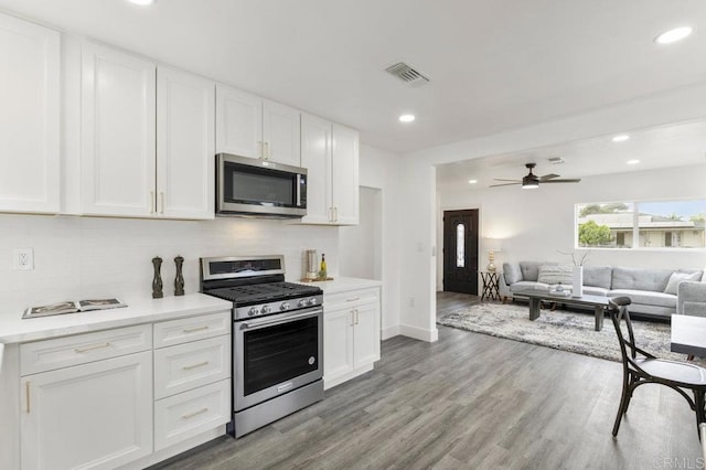 kitchen featuring ceiling fan, backsplash, white cabinets, and stainless steel appliances