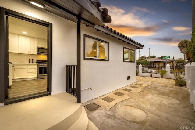 property exterior at dusk featuring a patio area