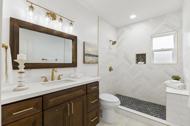 bathroom featuring toilet, vanity, and tiled shower