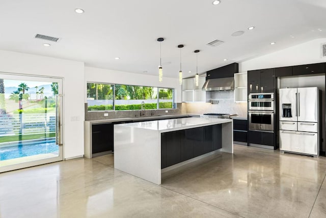 kitchen with appliances with stainless steel finishes, a kitchen island, wall chimney range hood, sink, and vaulted ceiling