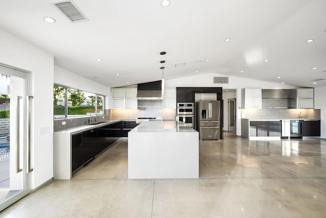 kitchen with appliances with stainless steel finishes, tasteful backsplash, decorative light fixtures, wall chimney exhaust hood, and a center island