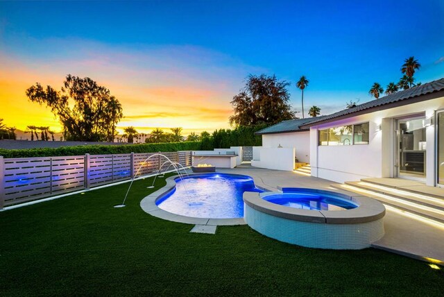 pool at dusk with an in ground hot tub and pool water feature