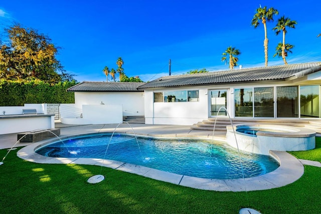 rear view of property with a swimming pool with hot tub, pool water feature, and a patio