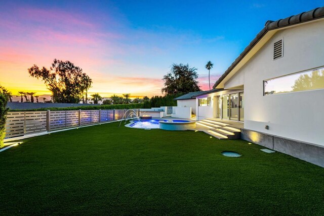 yard at dusk with a pool with hot tub and pool water feature