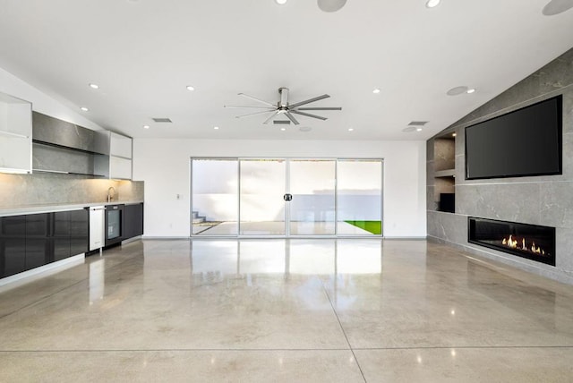 unfurnished living room featuring ceiling fan, vaulted ceiling, a fireplace, and sink