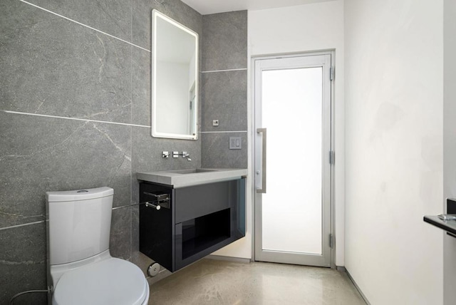 bathroom featuring toilet, tile walls, and vanity