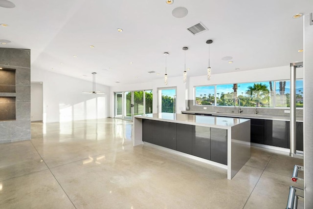 kitchen featuring ceiling fan, sink, a spacious island, and decorative light fixtures