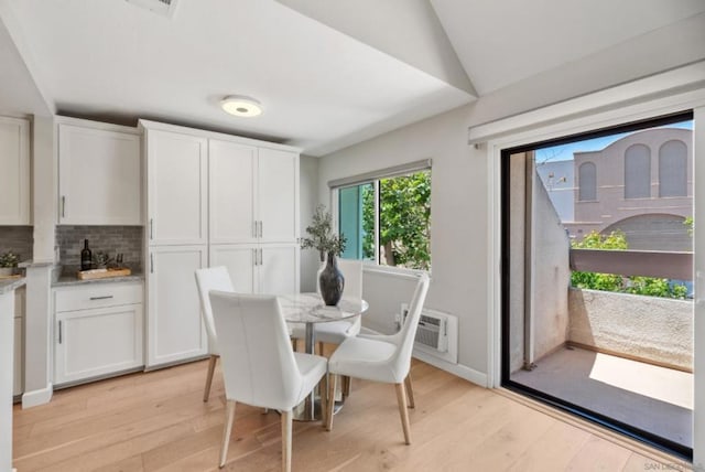 dining space featuring light hardwood / wood-style floors, an AC wall unit, and lofted ceiling