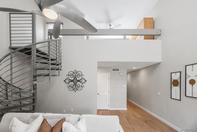 staircase featuring ceiling fan, a high ceiling, and hardwood / wood-style floors