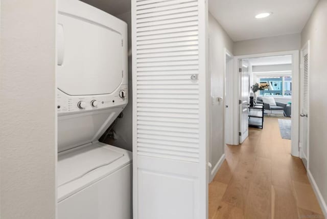 laundry room featuring light wood-type flooring and stacked washer / dryer