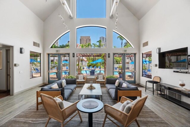 living room with a towering ceiling, hardwood / wood-style flooring, and french doors