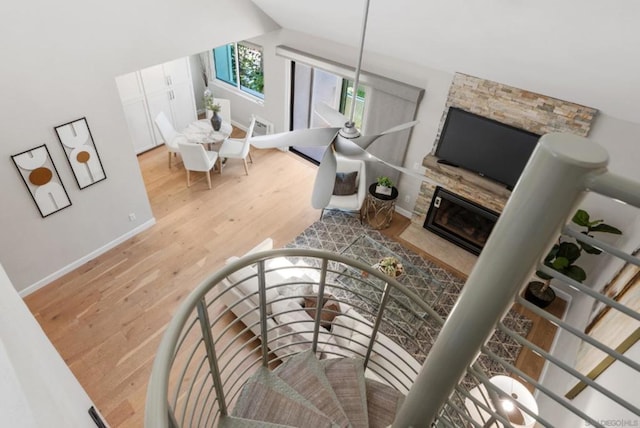 living room featuring vaulted ceiling, hardwood / wood-style flooring, and a stone fireplace