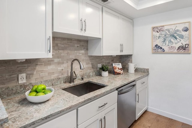 kitchen featuring backsplash, dishwasher, sink, light wood-type flooring, and white cabinets