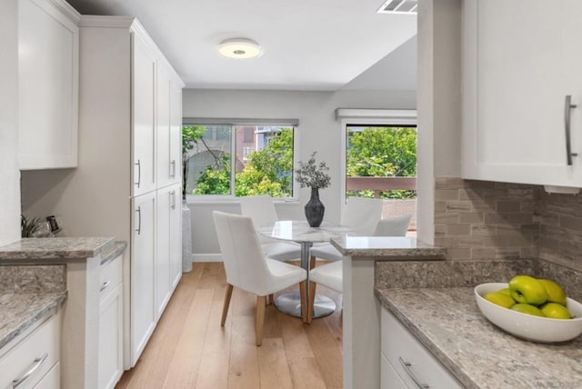 kitchen featuring light hardwood / wood-style floors, light stone countertops, and white cabinetry