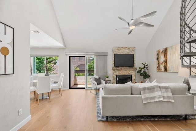 living room with hardwood / wood-style flooring, high vaulted ceiling, ceiling fan, and a fireplace