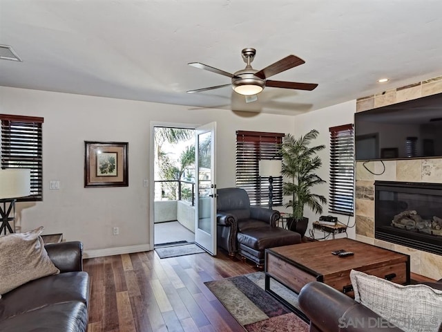 living room with ceiling fan, dark hardwood / wood-style flooring, and a tile fireplace