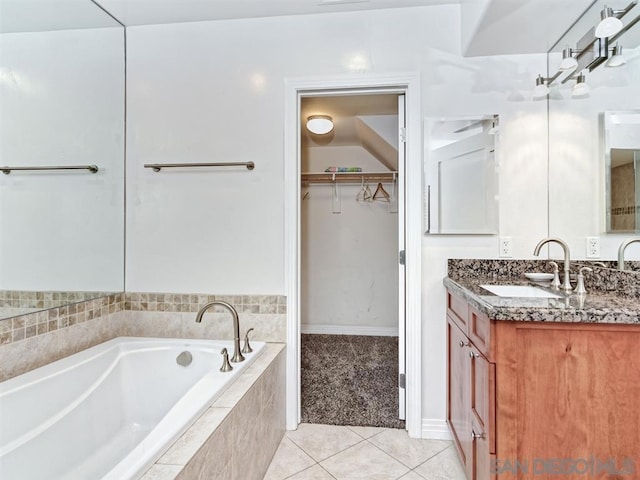 bathroom with a relaxing tiled tub, vanity, and tile patterned flooring