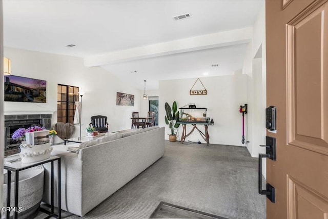 living room featuring a tiled fireplace and vaulted ceiling with beams