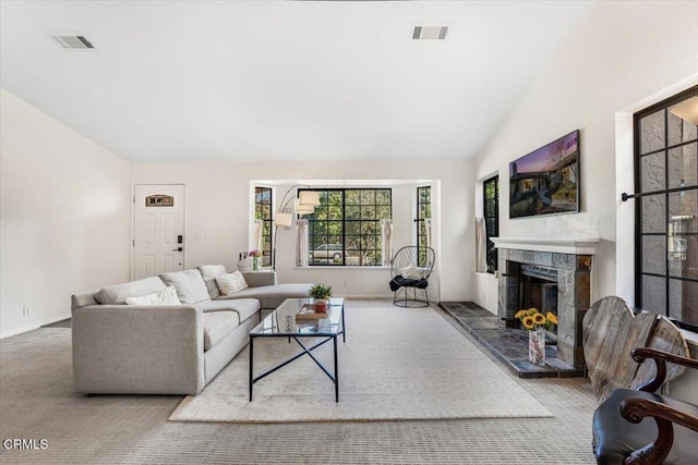 living room with vaulted ceiling, carpet flooring, and a tiled fireplace