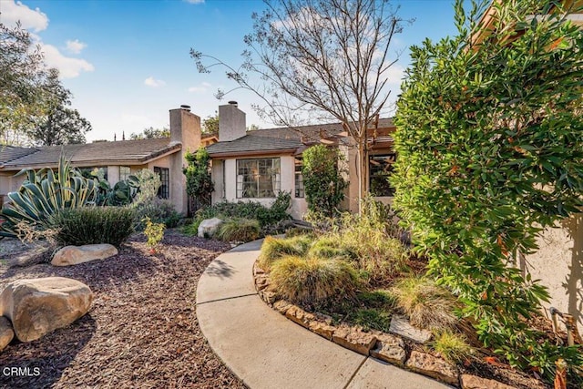 ranch-style home with a tile roof, a chimney, and stucco siding