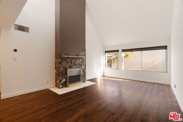 unfurnished living room with high vaulted ceiling, a fireplace, and wood-type flooring