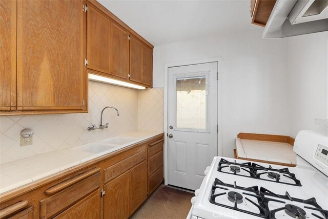 kitchen with tile counters, decorative backsplash, sink, and white range with gas cooktop